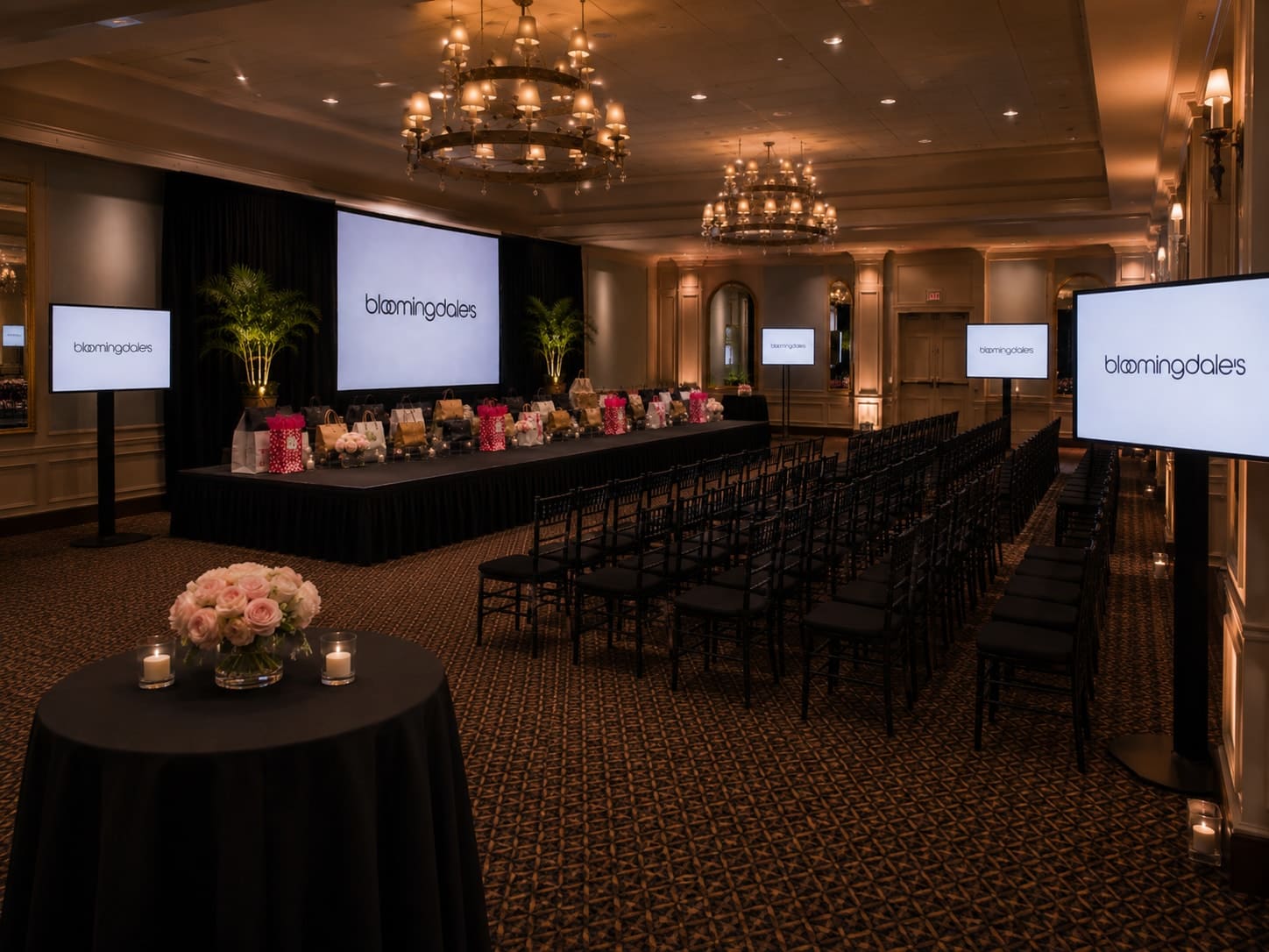 Brand activation in a chandeliered ballroom with flanking LED screens and a runway stage flanked by chiavari chairs